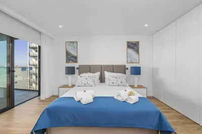 a white bedroom with a large bed with blue sheets at Terracos de Quarteira Blue by Real Properties in Quarteira
