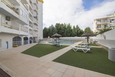 a courtyard with chairs and umbrellas and a pool at Hilcity in Albufeira