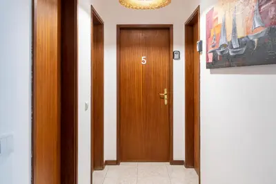 a hallway with a wooden door with the number five at Blife Ricardya private rooms in Faro