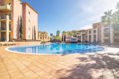 a swimming pool in a resort with palm trees and buildings at The Residences Vilamoura, Apartment Melissa in Vilamoura