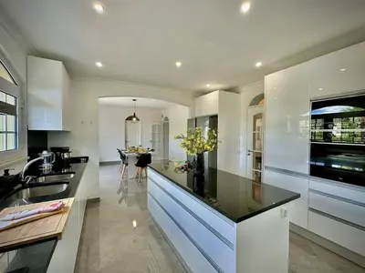 a kitchen with a black counter top and a table at Quarteira Premium Villa With Pool by Homing in Quarteira