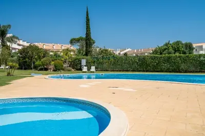 a large swimming pool with blue water in a yard at VILAMOURA Two Bedroom Near Praia Falésia in Quarteira