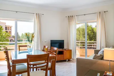 a living room with a table and chairs and a television at VILAMOURA Two Bedroom Near Praia Falésia in Quarteira