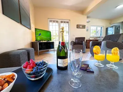 a bottle of wine and a bowl of fruit on a table at Villa Sarah by BeCherish in Quarteira