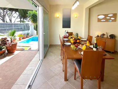 a dining room with a table and a pool at Villa Sarah by BeCherish in Quarteira