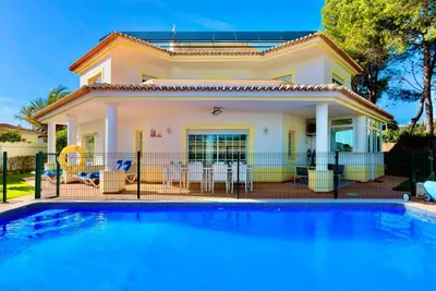 a villa with a swimming pool in front of a house at Casa Luna with Saltwater Pool in Olhos de Água