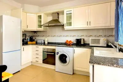 a kitchen with white cabinets and a washing machine at Casa Luna with Saltwater Pool in Olhos de Água