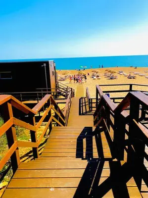 a wooden boardwalk leading to a beach with people at Casa Luna with Saltwater Pool in Olhos de Água