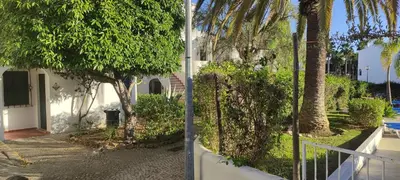 a white house with palm trees and a sidewalk at Casa de Praia em São Rafael in Albufeira