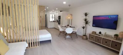 a living room with a bed and a tv on a wall at Casa de Praia em São Rafael in Albufeira