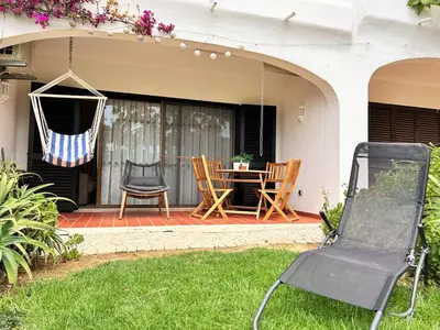 a porch with a hammock and a table and chairs at Casa de Praia em São Rafael in Albufeira