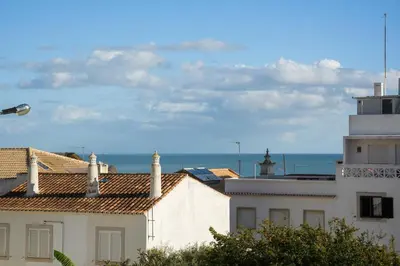 a view of roofs of buildings and the ocean at Amelie Old Town Apartment in Albufeira