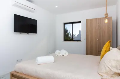 a bedroom with a bed with a tv on the wall at Amelie Old Town Apartment in Albufeira