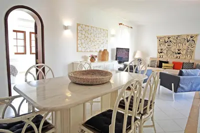 a dining room and living room with a table and chairs at VM Relax Beautiful villa with pool! VILAMOURA! in Quarteira