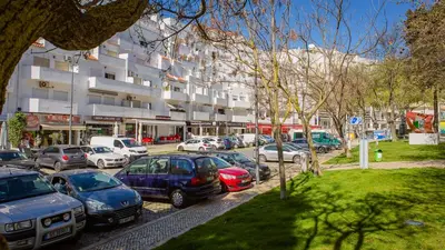 a parking lot with cars parked in front of a building at La Liberdad Loft in Albufeira