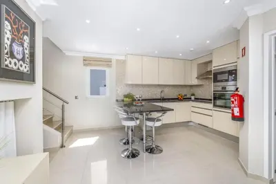 a kitchen with white cabinets and a table with stools at Stunning 2-Bedroom Beach Retreat in Vale do Lobo in Almancil
