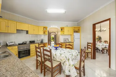 a kitchen with a table and chairs and a kitchen with yellow cabinets at Villa Vista Mar by Villa Plus in Terras Novas