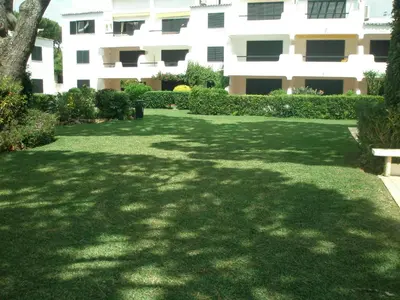 a green yard with a bench in front of a building at AA Apartamento Solar dos Pinheiros in Vilamoura
