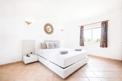 a white bedroom with a bed and a window at Villa Los Angeles by Algarve Vacation in Boliqueime
