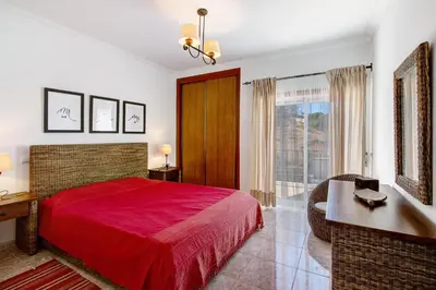 a bedroom with a red bed and a desk and a window at V2 a 400 m da Praia da Falésia in Albufeira