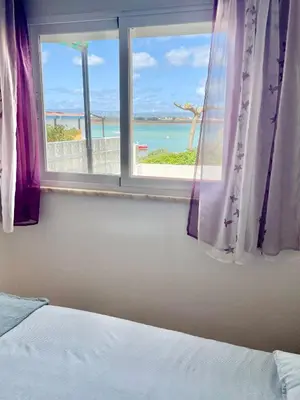 a bedroom window with a view of the ocean at Villa Cristipaulo in Praia de Faro