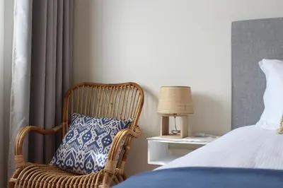 a wicker chair with a blue pillow sitting next to a bed at Villa Falésia casa da Sobreira in Albufeira