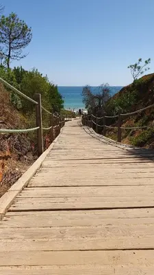 a wooden boardwalk leading to the ocean on a beach at Villa Falésia casa da Sobreira in Albufeira