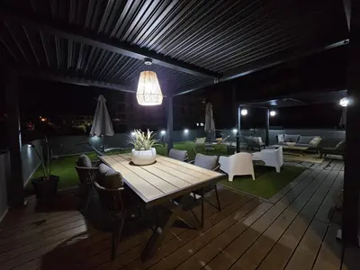 a wooden table and chairs on a patio at night at Paraíso Forte Novo in Quarteira