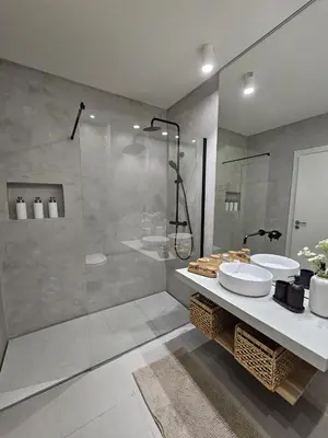 a bathroom with a glass shower and two sinks at Paraíso Forte Novo in Quarteira