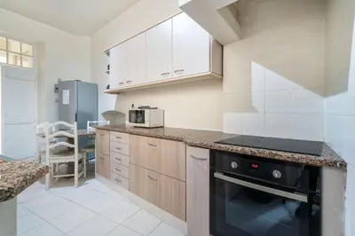 a kitchen with wooden cabinets and a black stove top oven at Blife Alicya private rooms in Faro