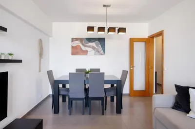 a dining room and living room with a table and chairs at Moderno e acolhedor com vista mar in Quarteira