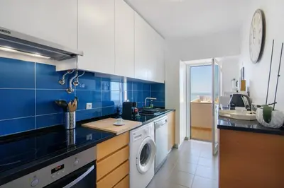 a blue and white kitchen with a washing machine at Moderno e acolhedor com vista mar in Quarteira