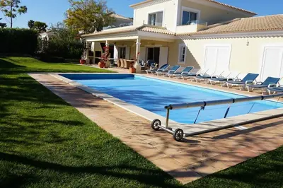 a swimming pool in front of a house at Luxury Private 5 bedroom Villa pool, golf, Algarve in Quarteira