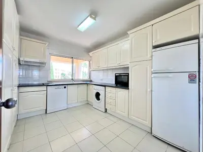 a kitchen with white cabinets and a washer and dryer at Home Out - Vilamoura Beach Apartment - Duplex in Quarteira