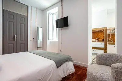 a white bedroom with a bed and a chair at Dona Simone Boutique Suites & Studios - by @ rita's place in Faro