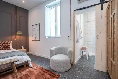 a bedroom with a bed and a chair and a window at Dona Simone Boutique Suites & Studios - by @ rita's place in Faro
