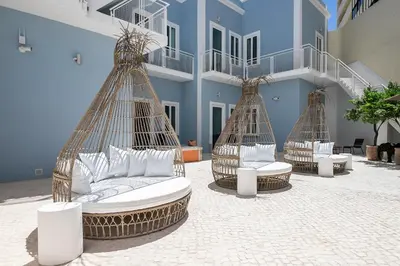 three rattan beds with white pillows in front of a building at Dona Simone Boutique Suites & Studios - by @ rita's place in Faro