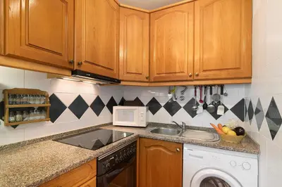 a kitchen with wooden cabinets and a sink and a dishwasher at Apartarment Azur in Albufeira