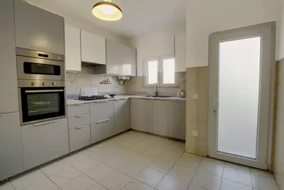 a kitchen with white cabinets and a large doorway at Townhouse in Quarteira in Quarteira
