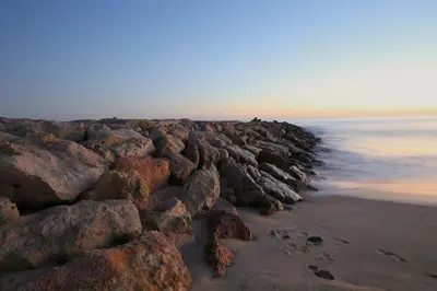 a group of rocks on a beach near the water at Townhouse in Quarteira in Quarteira