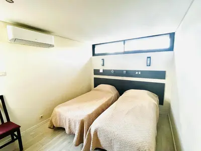 two beds in a small room with a window at Pe do Lago cosy apartment in Quarteira