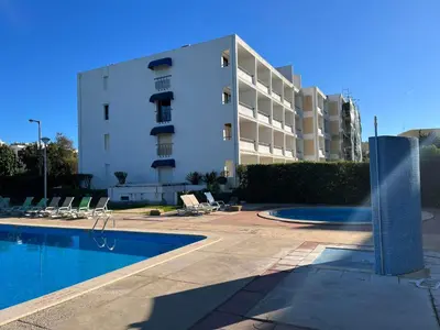 a building with a swimming pool in front of a building at Pe do Lago cosy apartment in Quarteira