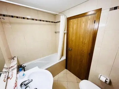 a bathroom with a toilet and a tub and a sink at Pe do Lago cosy apartment in Quarteira