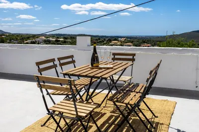 a table with chairs and a bottle of wine on a balcony at Casa Ladeira in Loulé