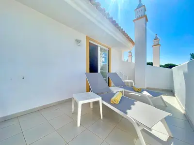 a balcony with chairs and a table and a window at Casa Falésia - 150 meters from Falésia Beach in Albufeira
