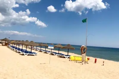 a beach with chairs and umbrellas and the ocean at Victory Village Club,Quinta do Lago in Loulé