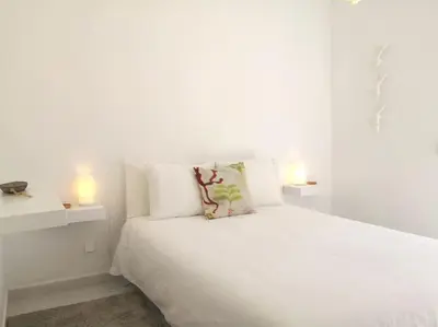 a white bedroom with a white bed and two lights at Ancão beach duplex with private garden in Almancil