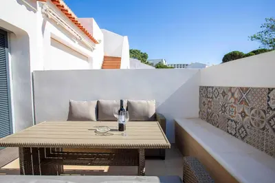 a table with a glass of wine on a patio at Villa Golden Falésia by HelloVacations in Albufeira