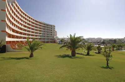 a building with palm trees in a field of grass at Exciting Albufeira Studio in Albufeira