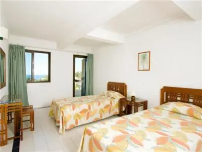 a bedroom with two beds and a table and windows at Superb Apartments 2 Bedroom in Olhos de Água